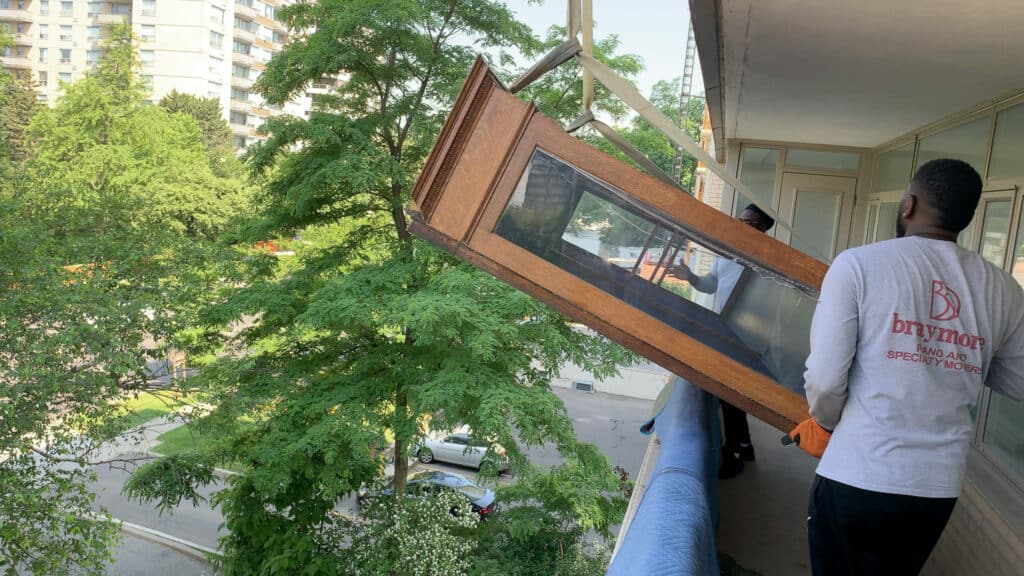 Using a knuckle crane to hoist a dining room china unit onto a condo balcony