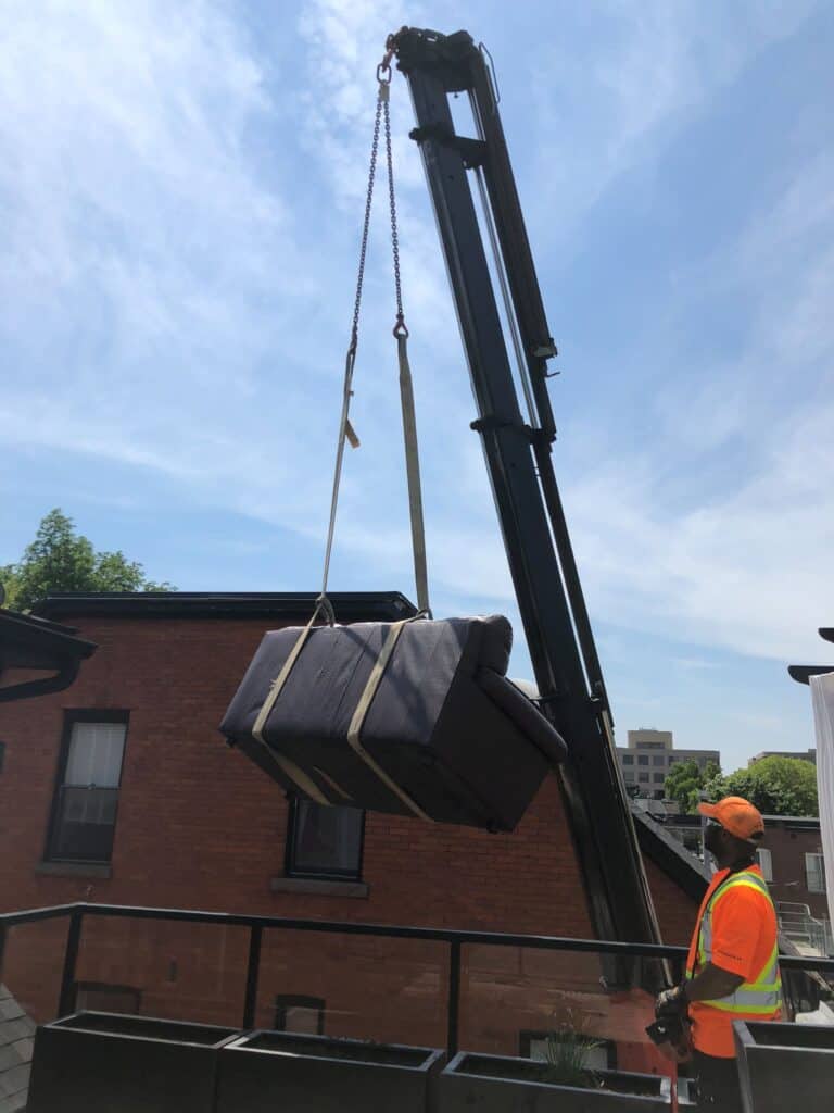 Craning a sofa onto a balcony of a house