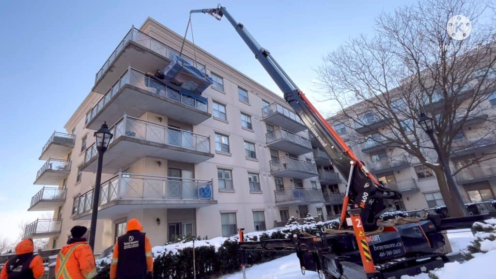 Using a spider crane to lift a china unit up onto a balcony of an apartment building