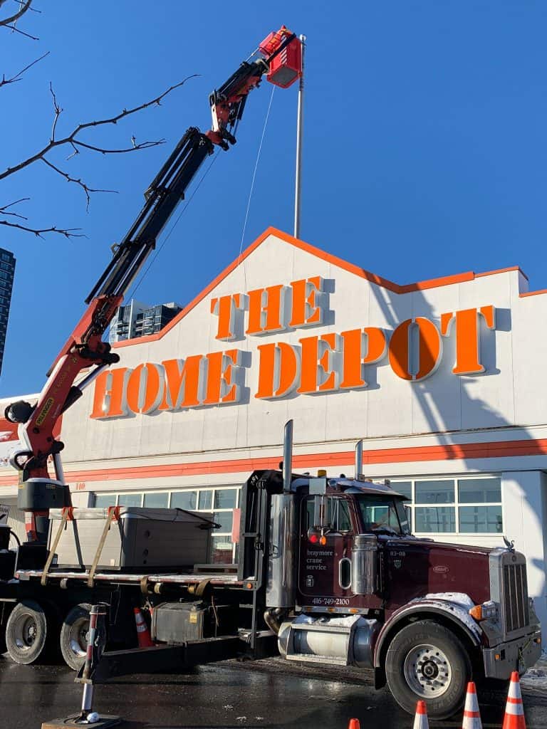 Using a manbasket on a knuckle crane to service a flag pole on a building