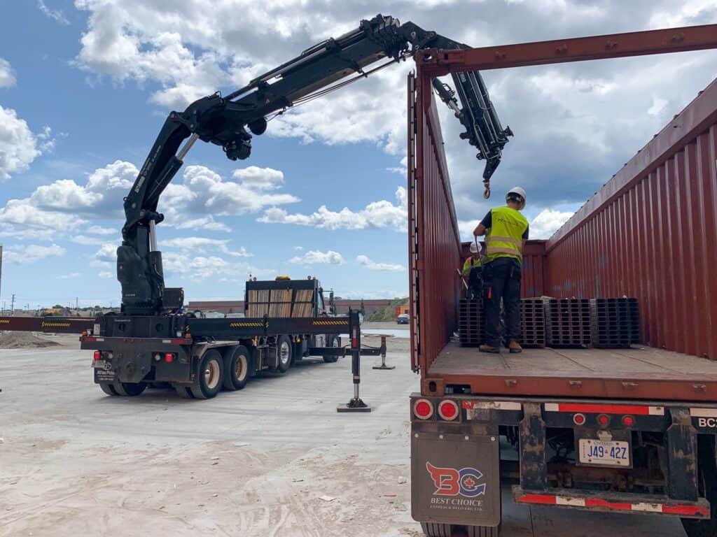 Using a knuckle crane to lift steel materials out of an open top container