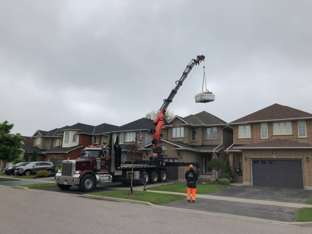 Craning a hot tub over a house in a sub division