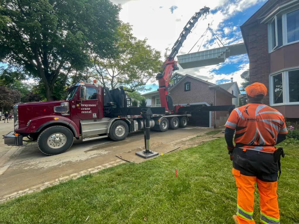 Using a large knuckle crane to lift a fiberglass pool over a house