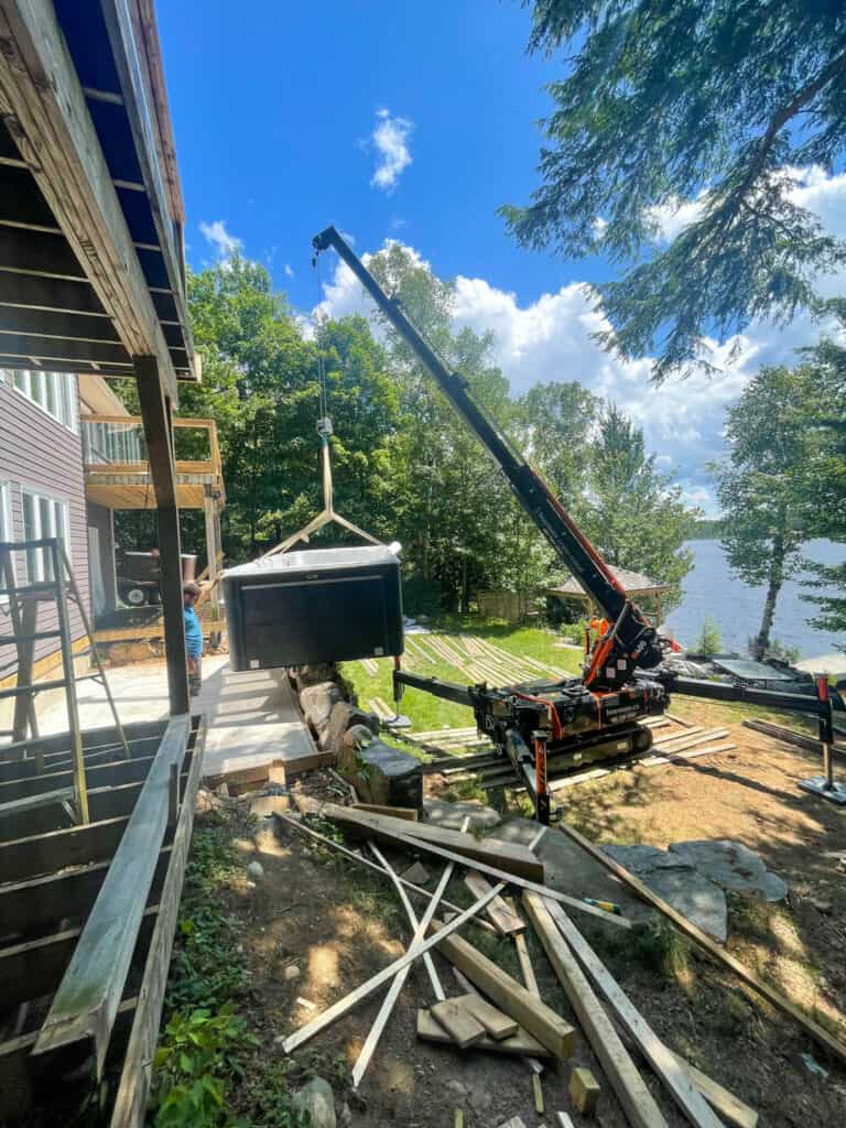 Spider crane lifting a swim spa onto a deck at a cottage in the Muskoka's.