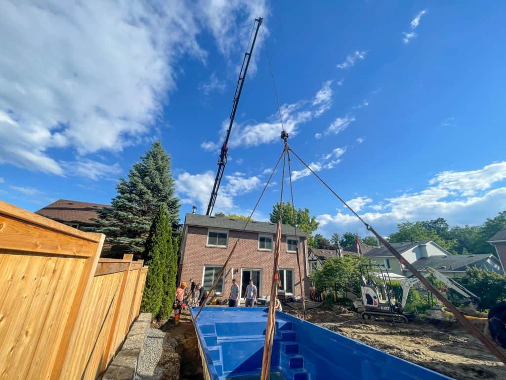 Crane a large pool over a home and into a sunken pit