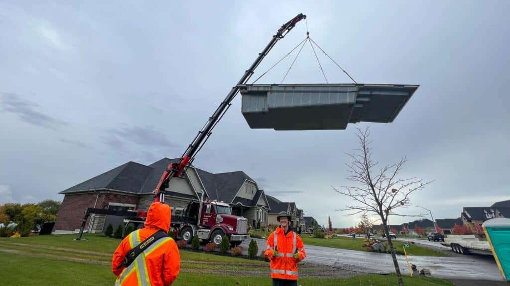 Using a large knuckle crane to lift a swimming pool over a house