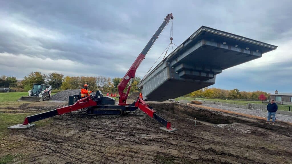 Using a spider crane to place a swimming pool into the ground