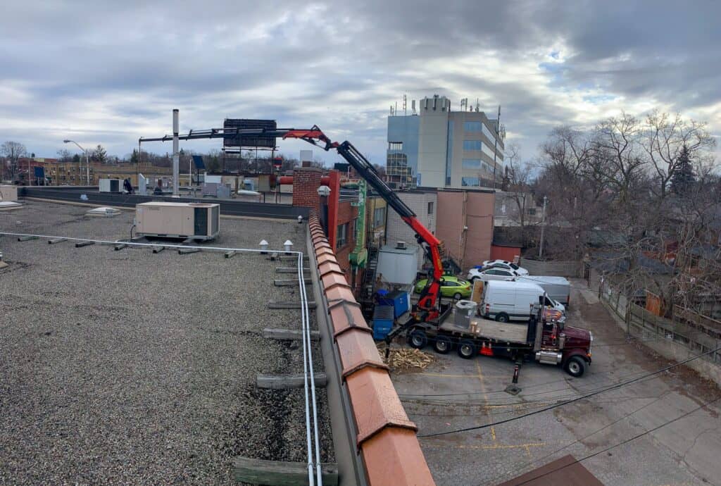 Using a smaller knuckle crane to reach further onto a roof of a commerical building.