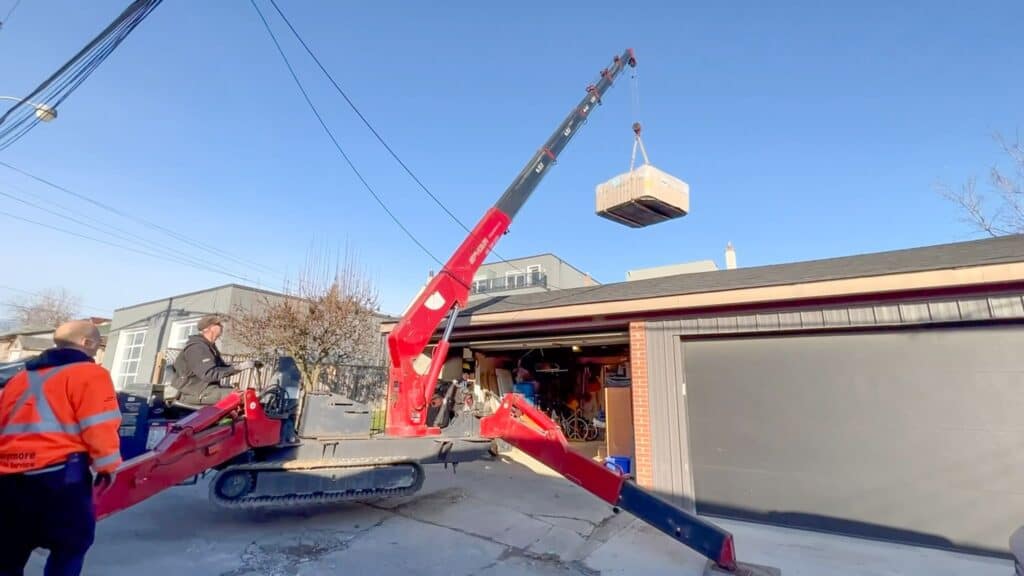 Using a spider crane to lift a hot tub over a garage in a back laneway, because large crane could not be used on the street.