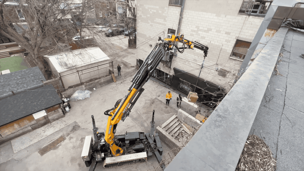 Using a spider crane to lift HVAC unit and accessories in a back laneway where regular city cranes cannot fit.