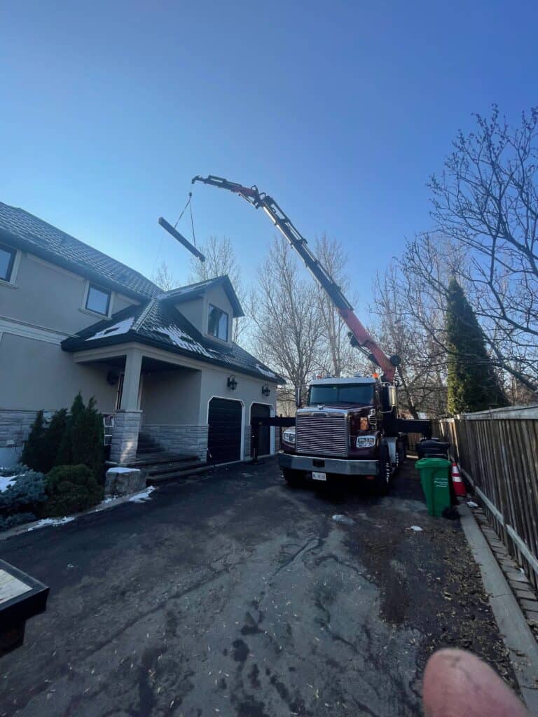 Using a knuckle crane to lift a large steel beam over a house