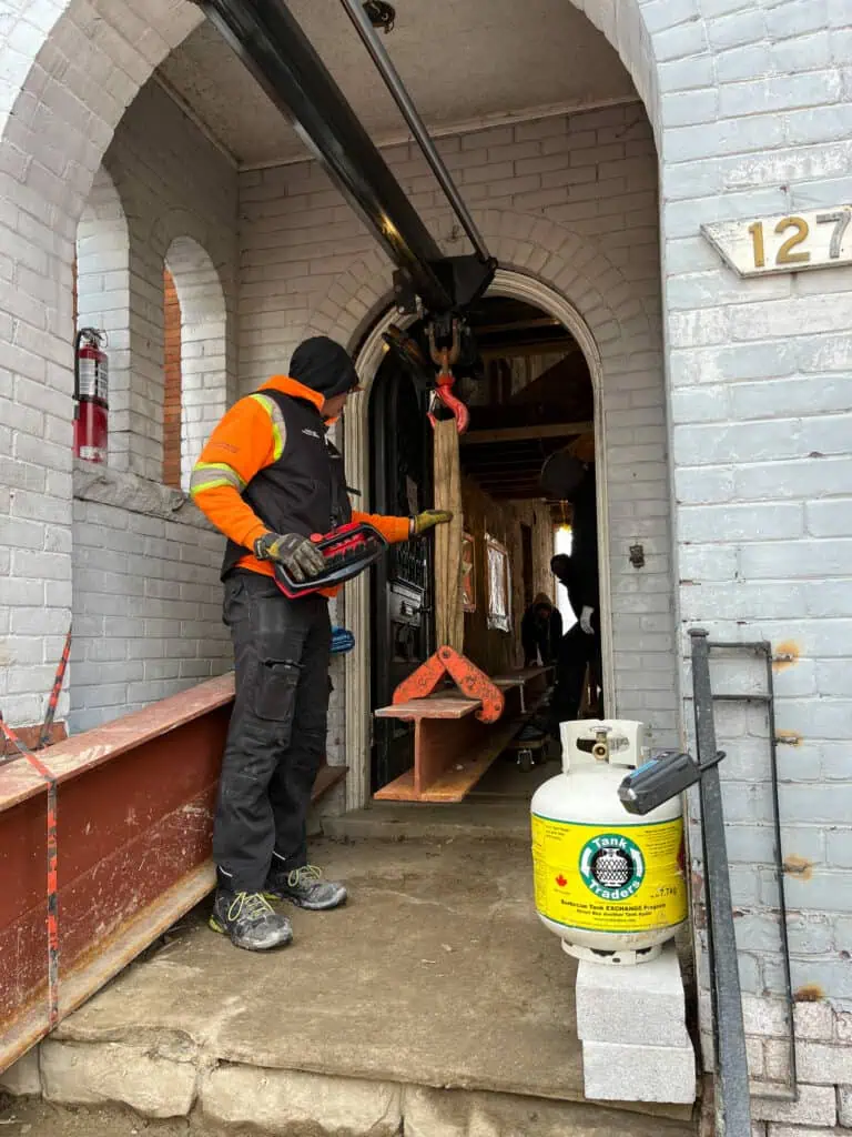 Using a knuckle crane to feed a large steel beam into a house