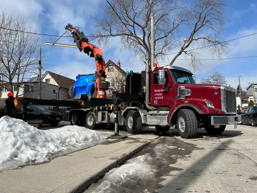 Using a knuckle crane to lift a steel beam into a yard