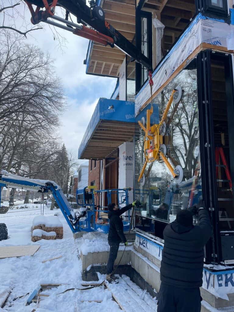 Using a spider crane to lift a large window pane into place on a major renovation in Toronto