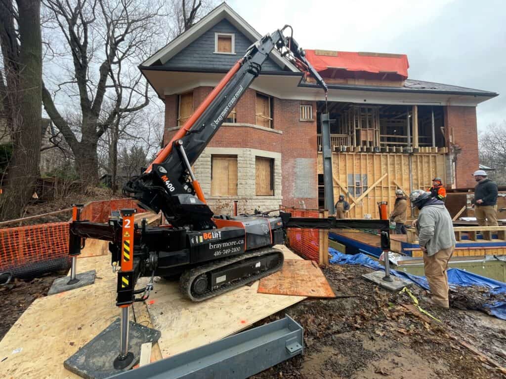 Using a spider crane at a construction site in Toronto to move and place steel beams